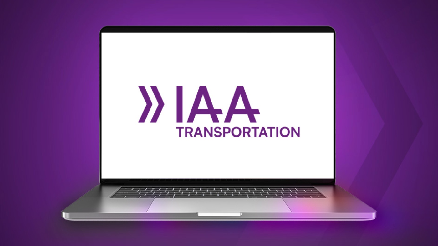 Laptop mit dem Logo IAA Transportation vor violettem Hintergrund.