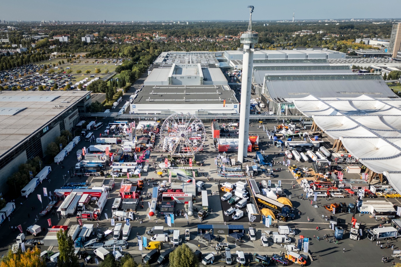 Aerial view of a large trade fair with trucks, booths and a Ferris wheel.