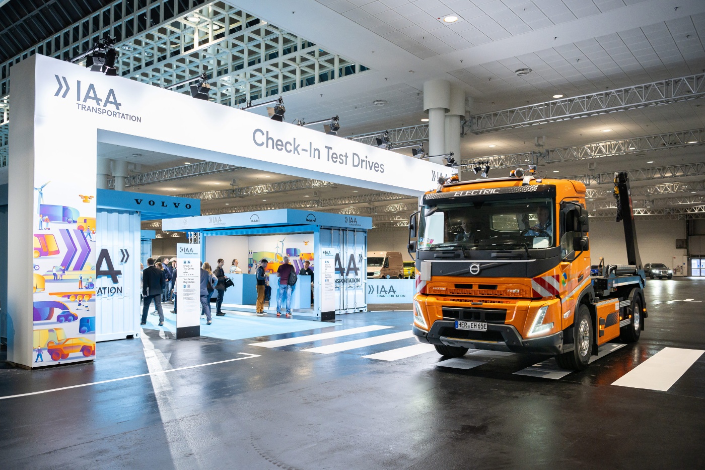 Oranger Elektro-Lkw in einer modernen Messehalle.