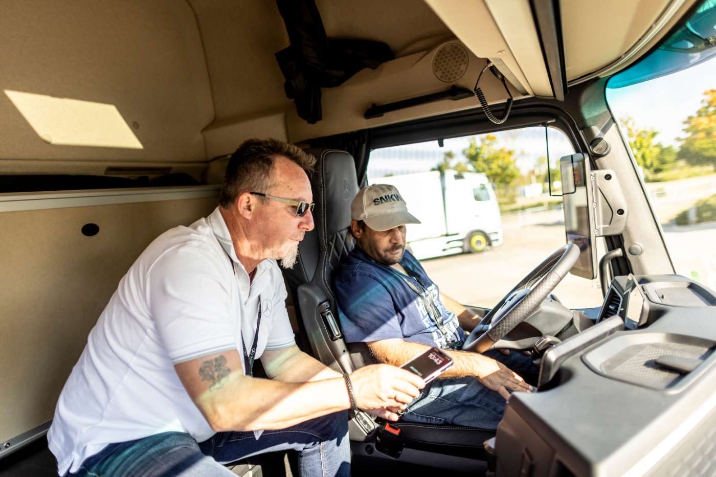 Zwei Männer bedienen die Technik in einer Lkw-Kabine.