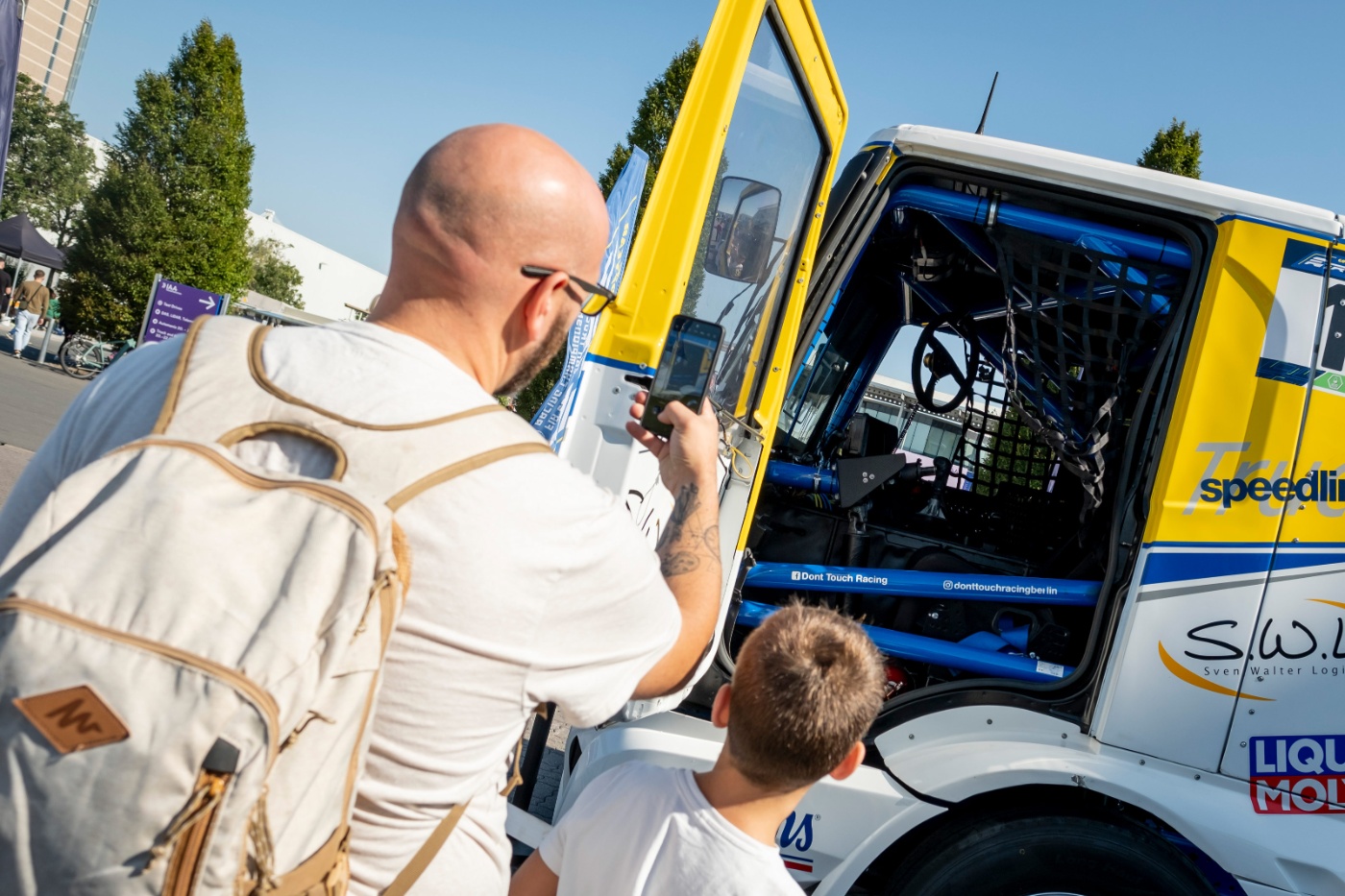 Mann fotografiert eine Lkw-Kabine, Kind schaut hinein.