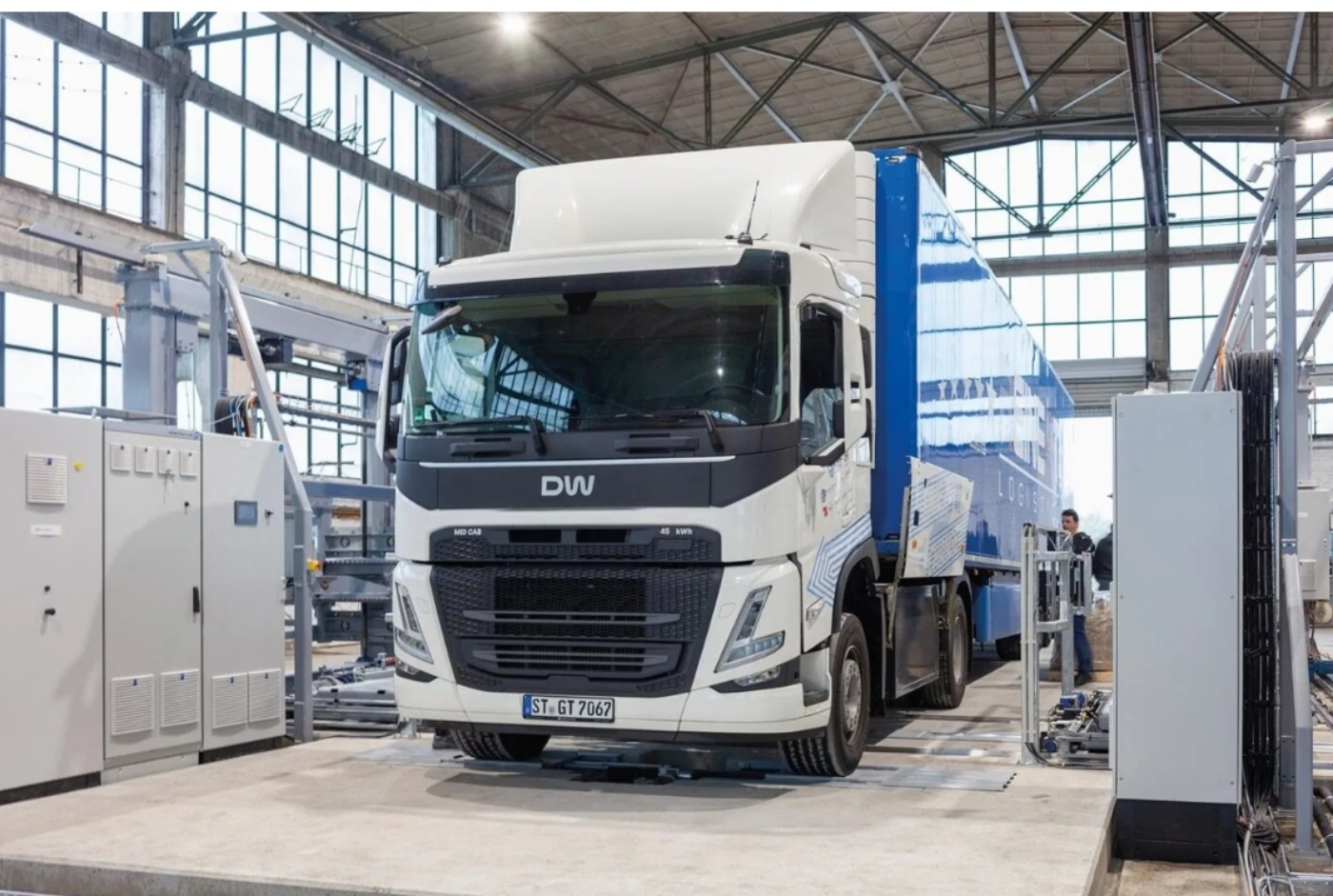 Elektro-Lkw in einer Werkstatt oder Prüfanlage mit Geräten und einem Techniker in der Nähe.