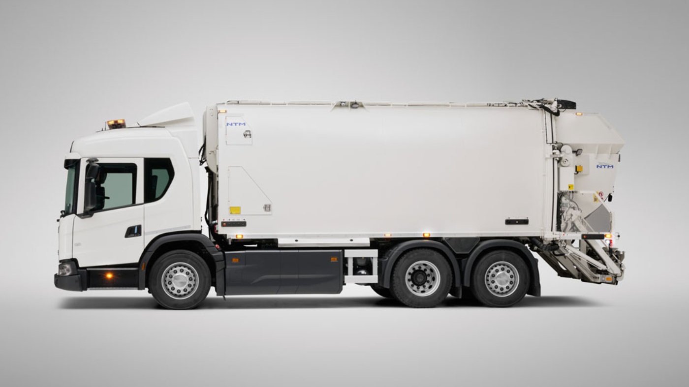 A white Scania garbage truck is shown from the side in a studio with a neutral background.