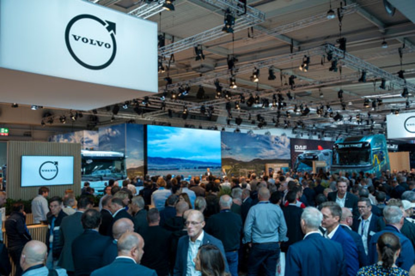 Large crowd at a Volvo exhibition booth with trucks and screens at a trade fair.