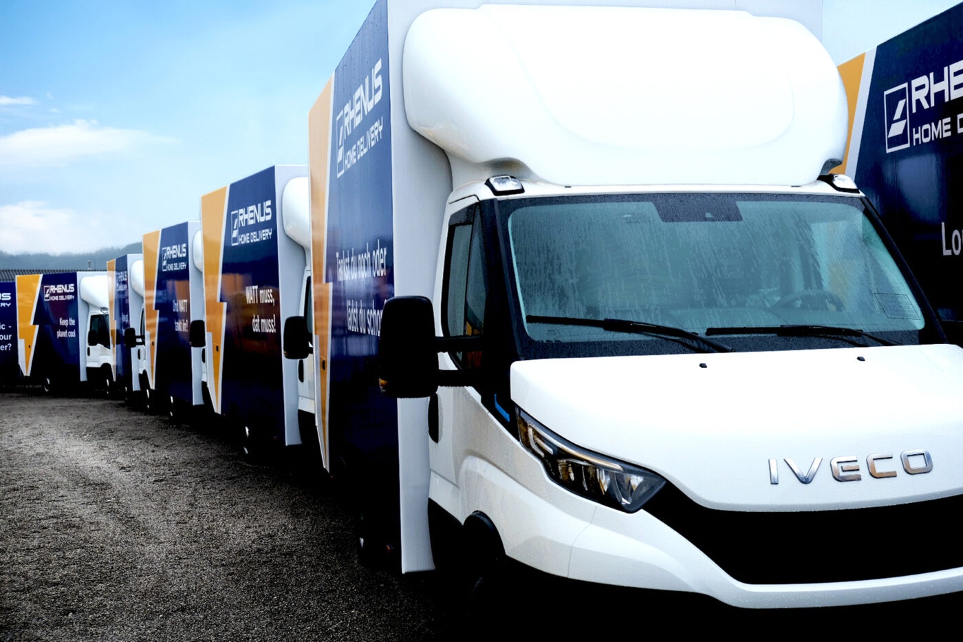 Row of Iveco delivery trucks parked in line at a logistics site.