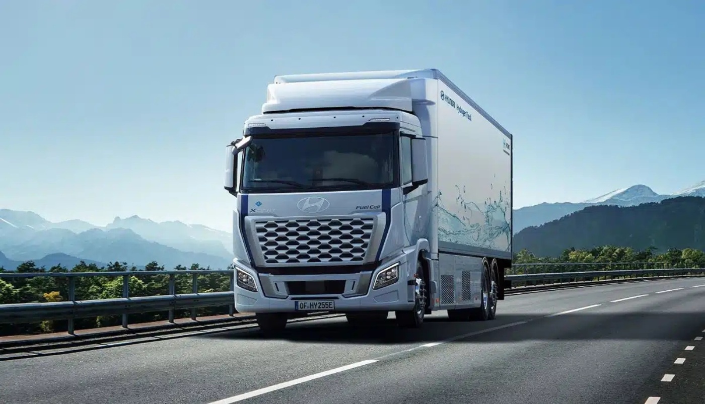Hydrogen-powered Hyundai truck driving on a highway with mountains in the background.