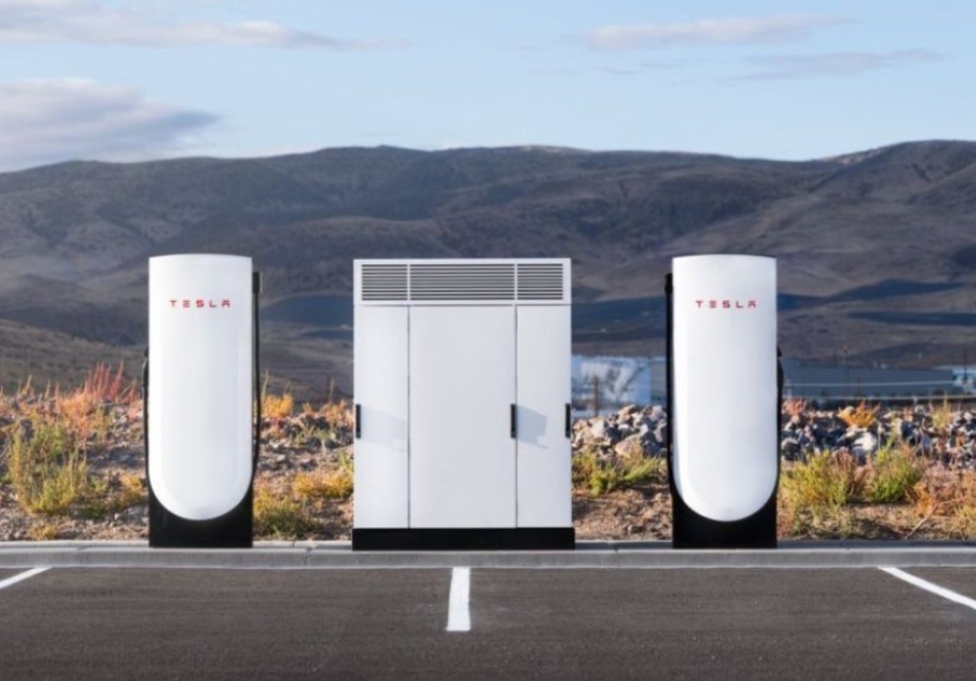Tesla-Supercharger mit zwei Ladesäulen und zentraler Einheit auf einem Parkplatz.