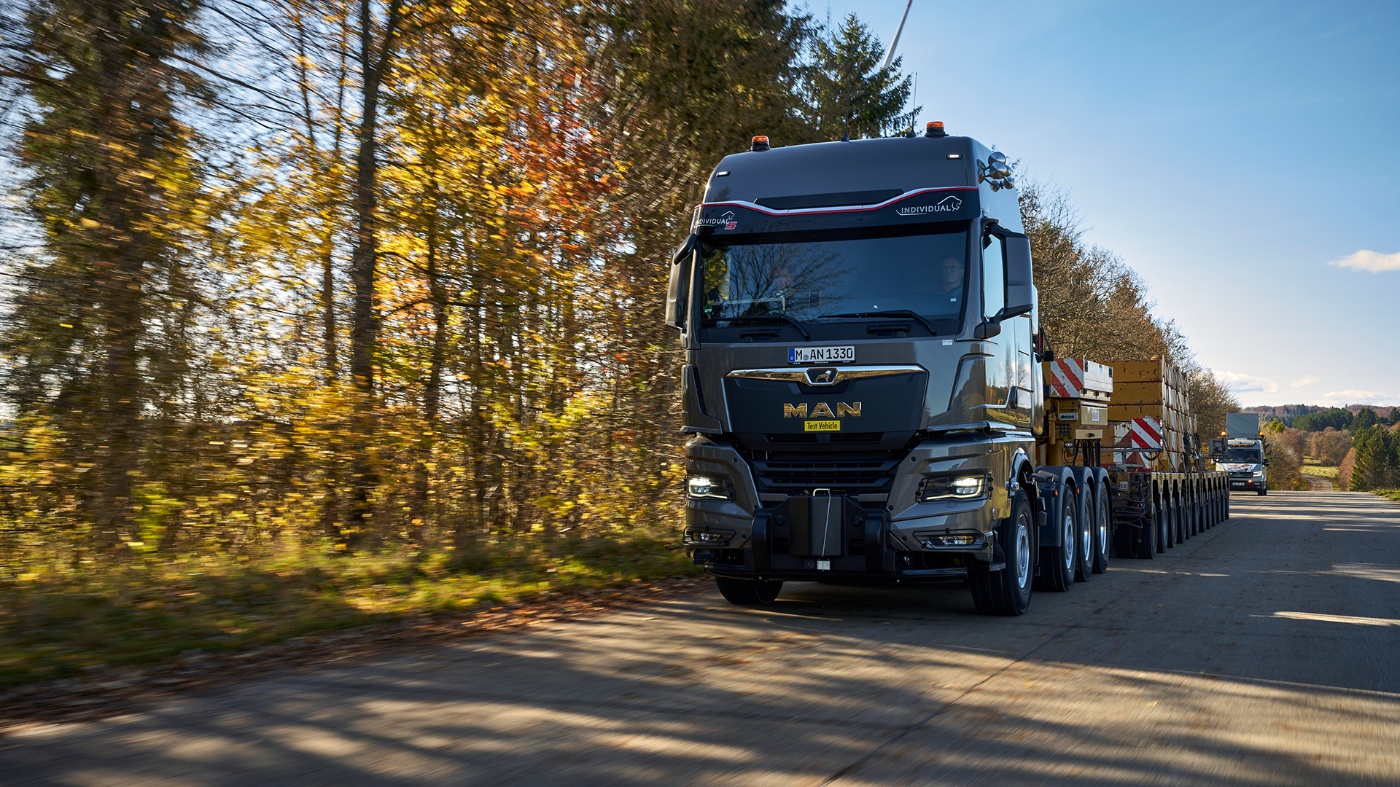 MAN truck with heavy load driving on a rural road in autumn.
