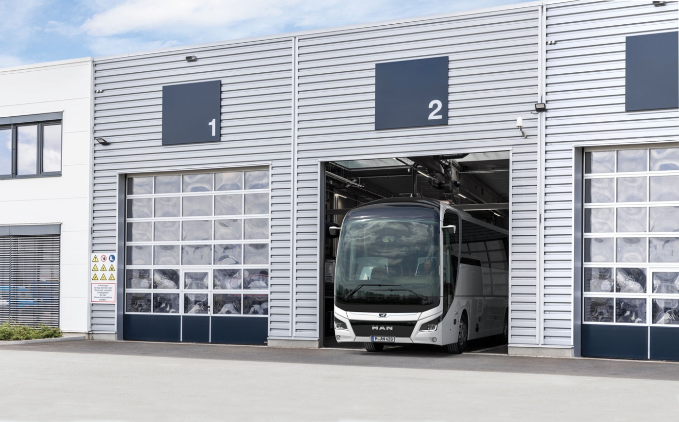 A bus stands in a numbered garage bay of a modern service building.