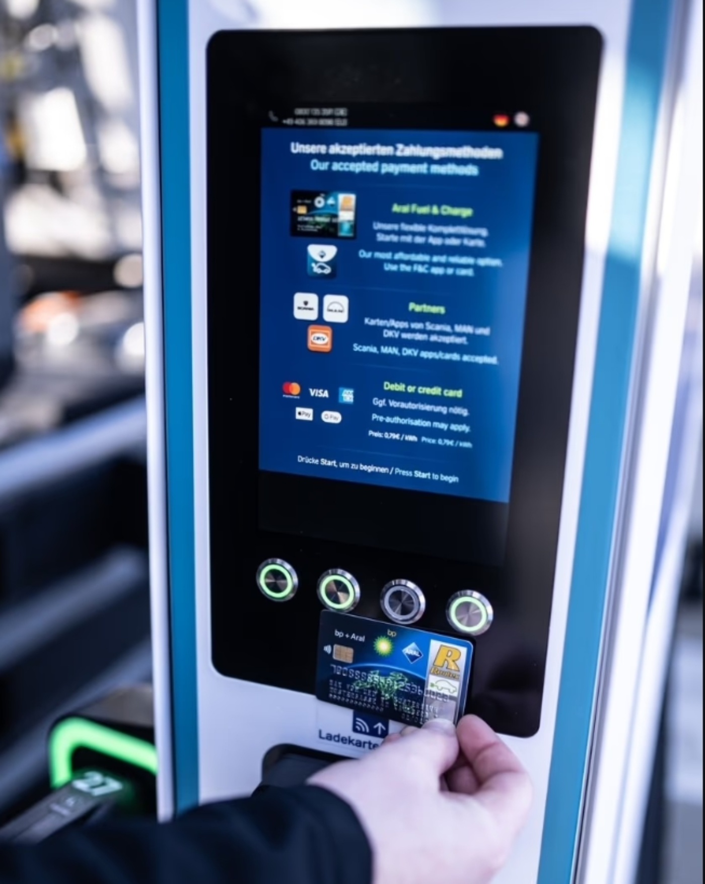 Eine Person bedient einen Touchscreen an einer E-Ladestation.