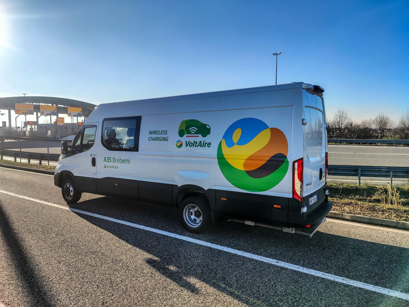 An Iveco van with VoltAir branding is parked near a highway toll station.
