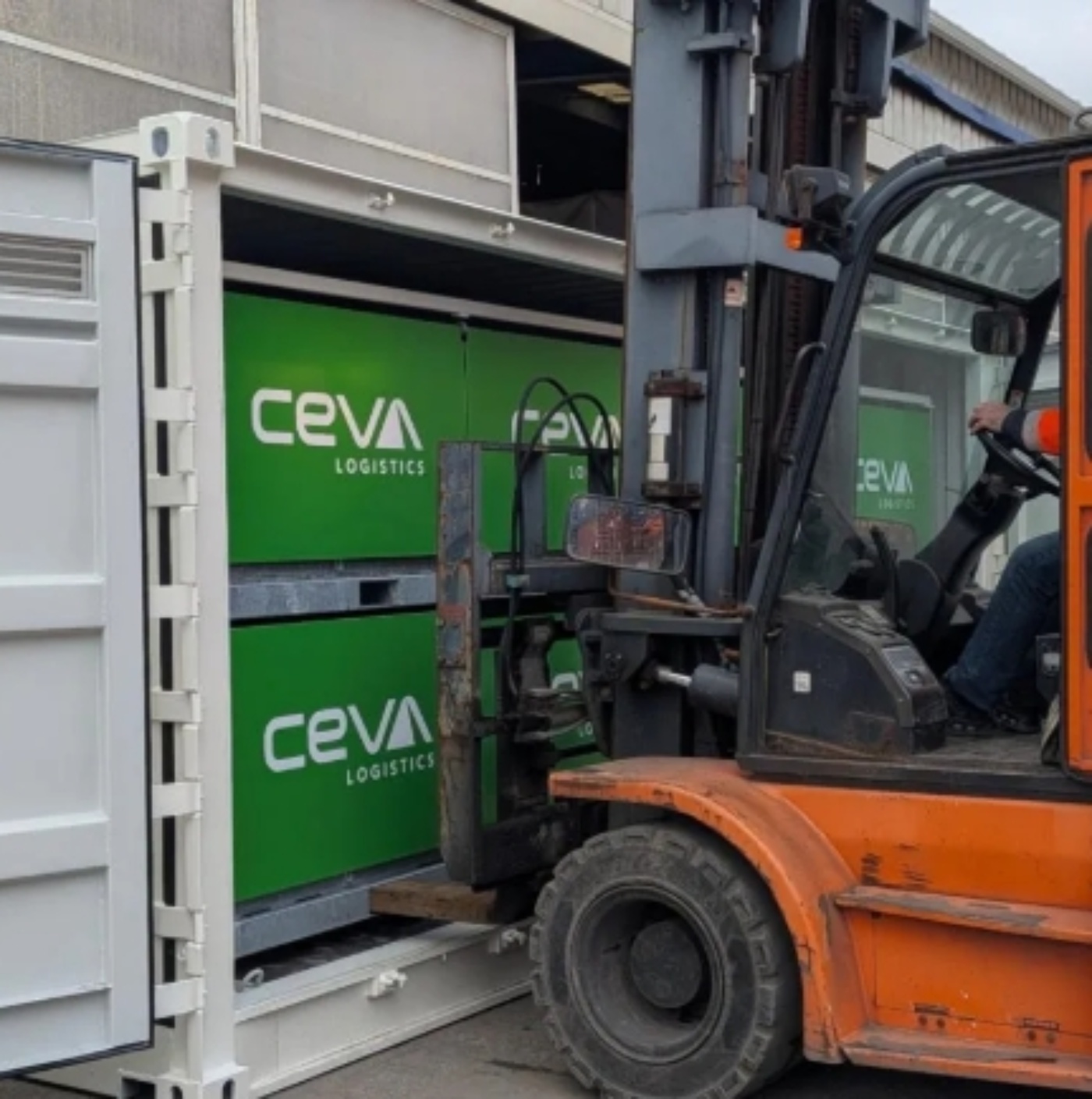 A forklift loads a CEVA Logistics container at a warehouse.