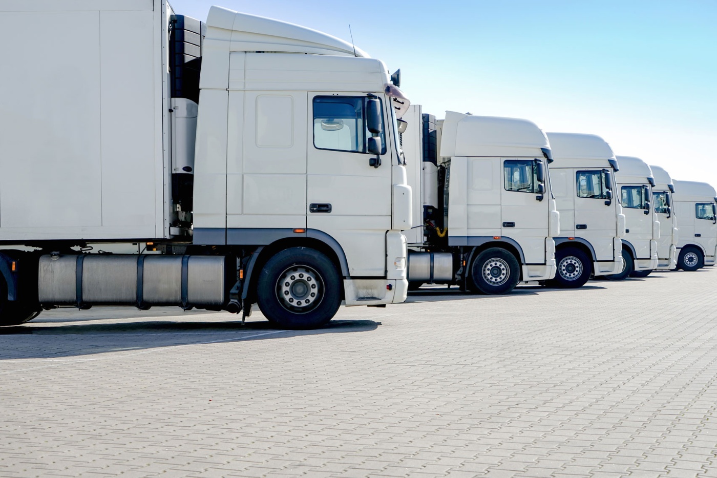 Row of white semi-trucks parked on a paved lot