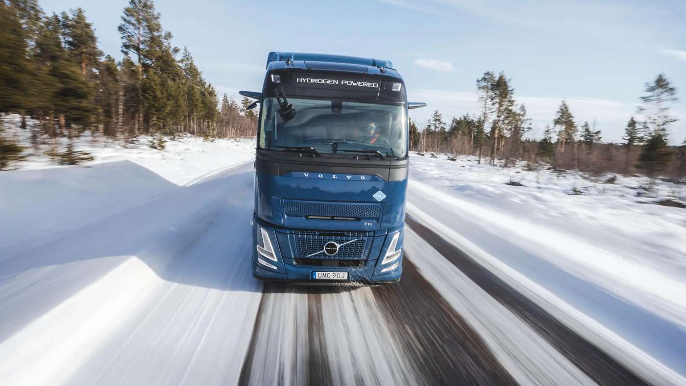 Volvo truck driving toward the camera on a snowy road in a winter landscape.