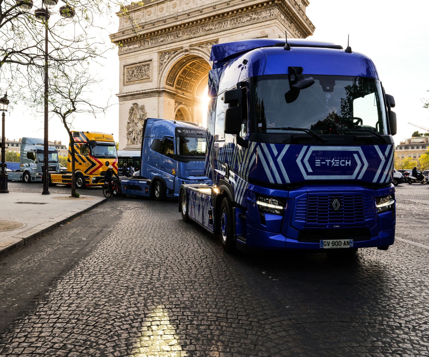 Blue electric truck driving past the Arc de Triomphe in Paris.