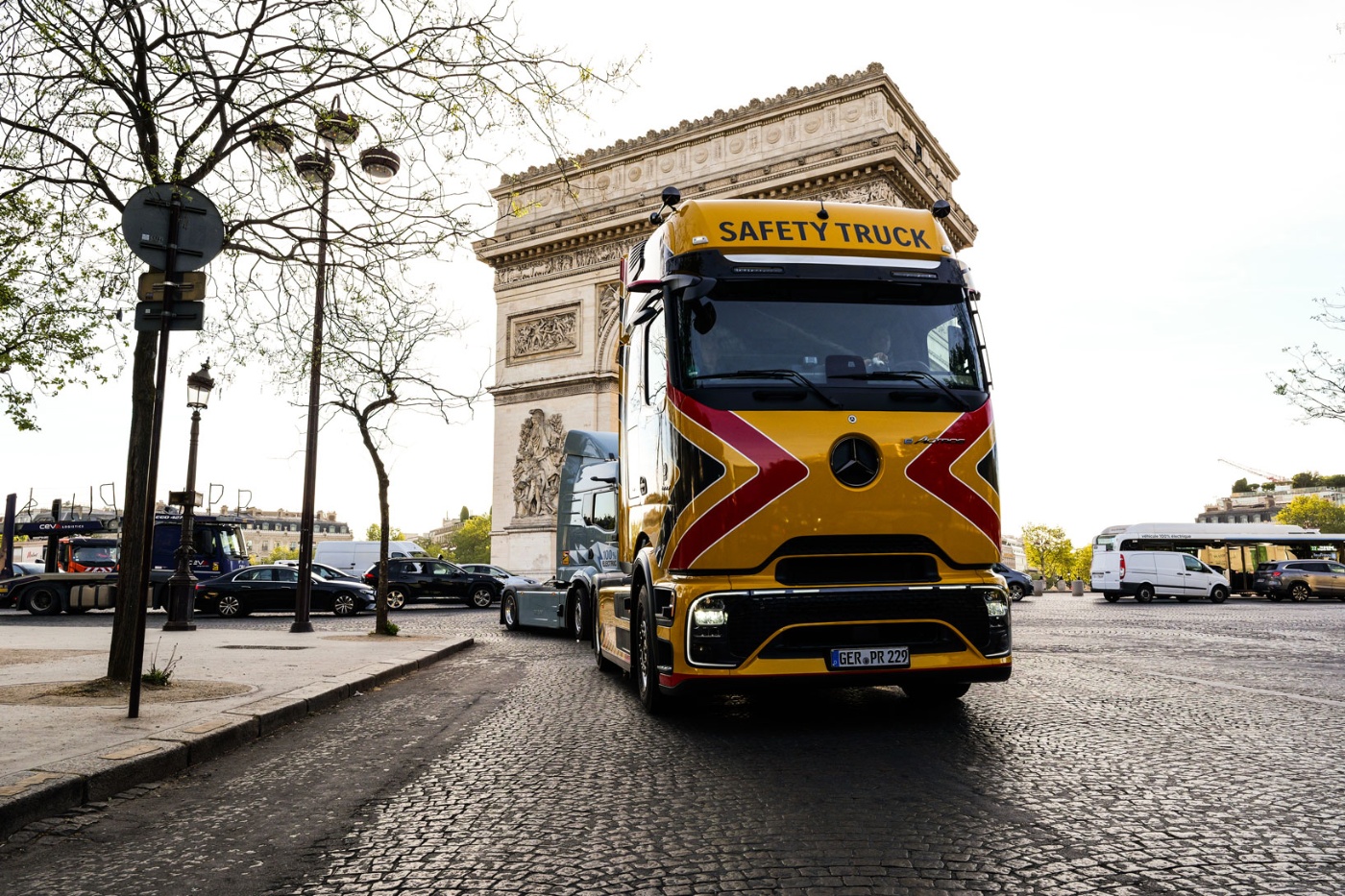 Yellow safety truck driving past the Arc de Triomphe in Paris.
