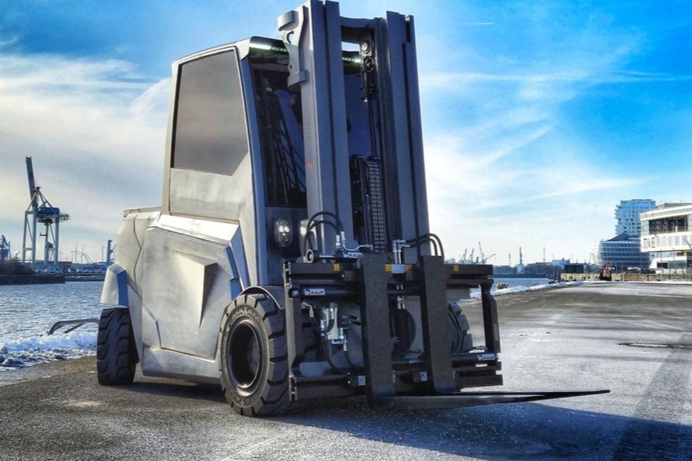 Large industrial forklift parked at a harbor loading area.