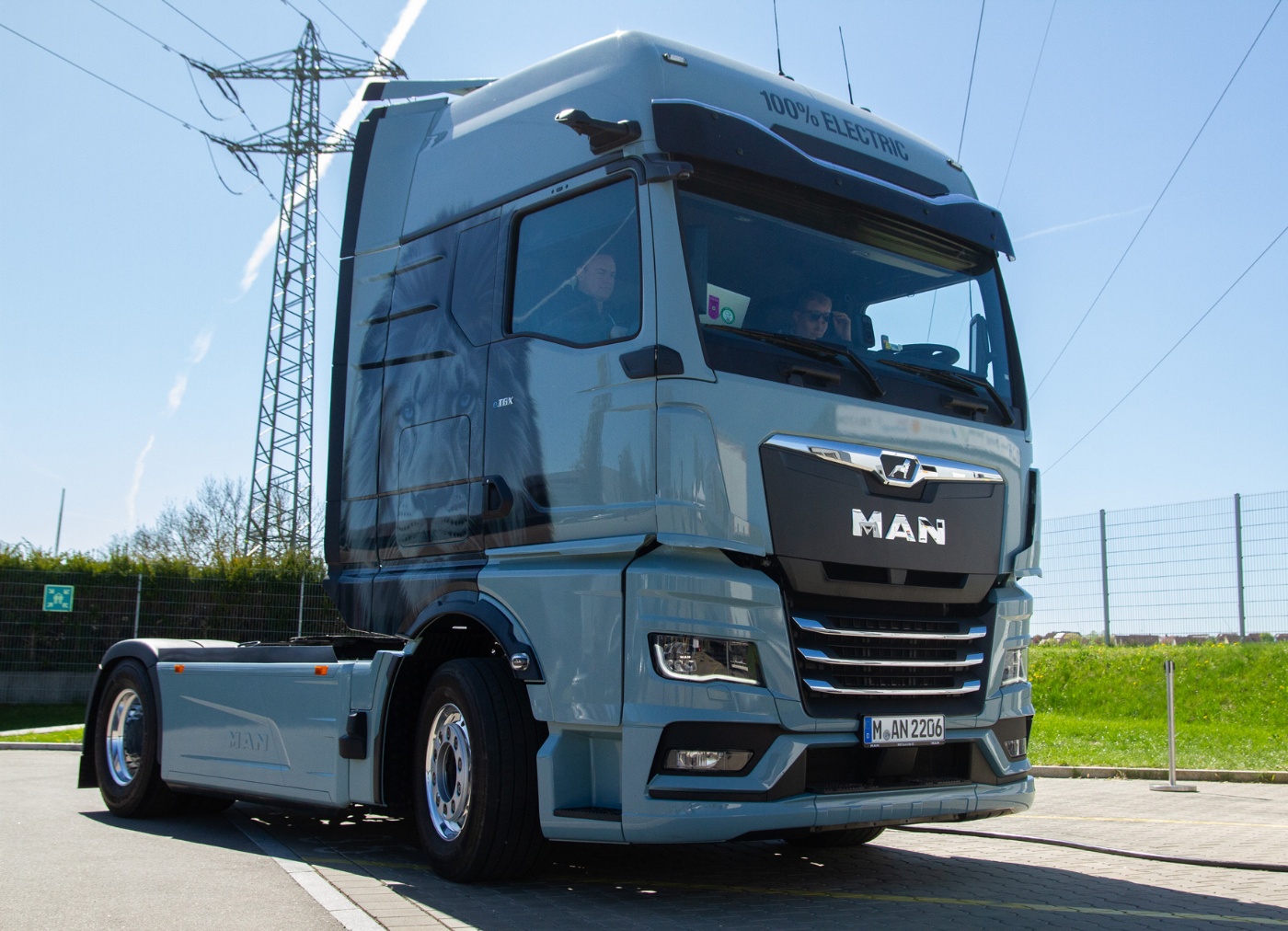Hellblauer MAN Lkw in schräger Frontansicht auf offener Straße.