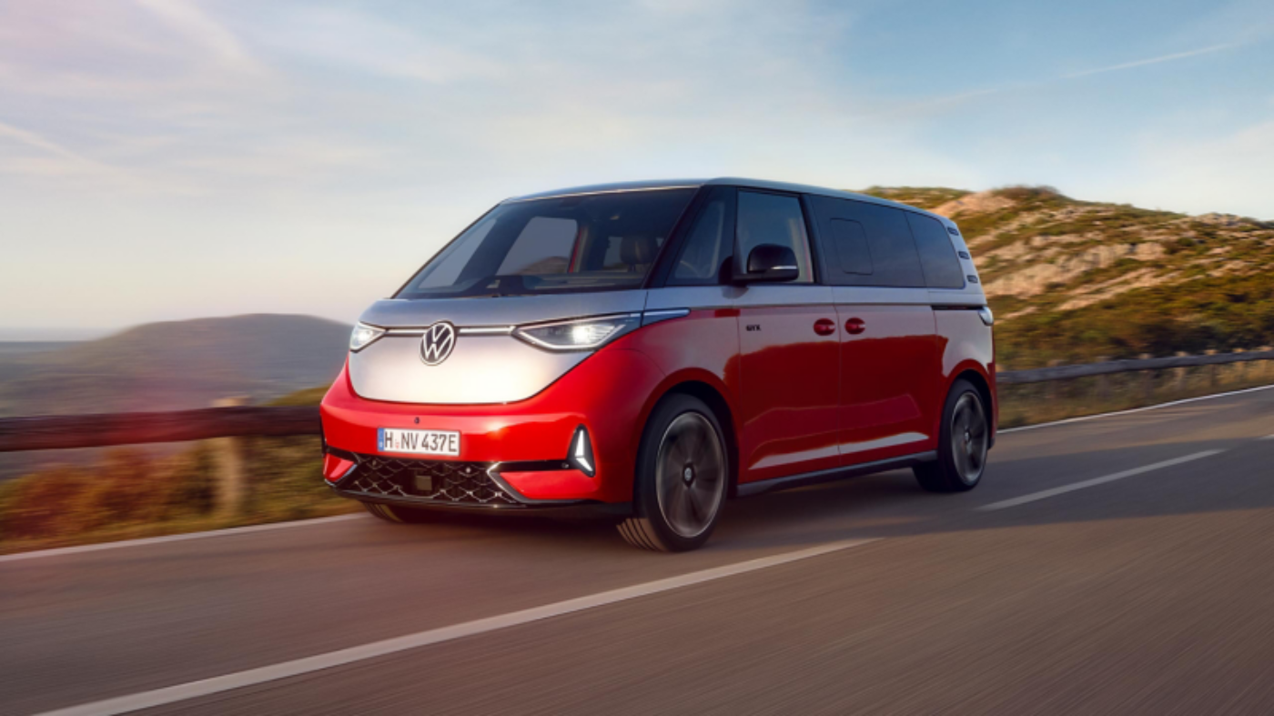 Red and white Volkswagen van driving on a coastal road.