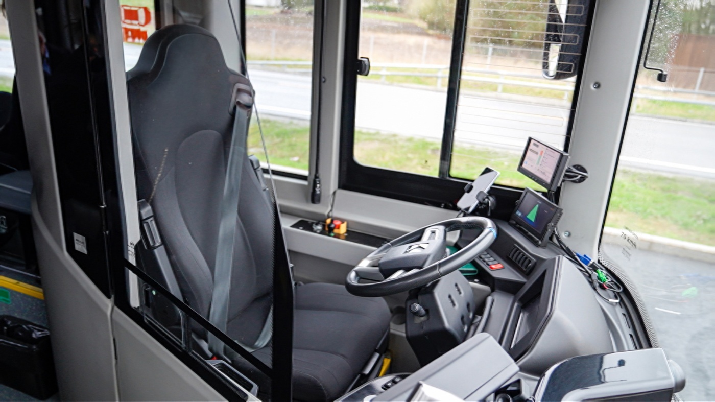 Fahrersitz und Kontrollbildschirme in einem autonomen Bus.