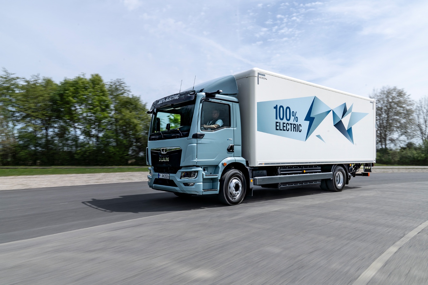 MAN Elektro-Lkw mit Aufschrift „100% Electric“ fährt auf einer Straße.