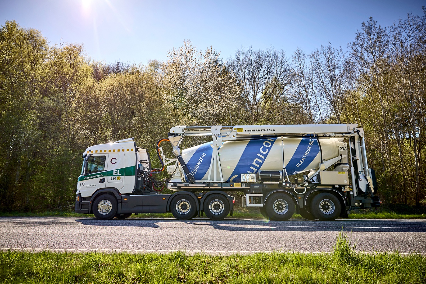 Electric Unicon concrete mixer truck labeled “Emissionsfri Bil” parked on a rural road.