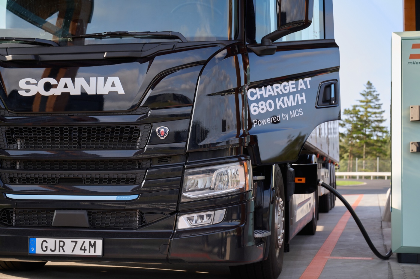 Scania Elektro-Lkw lädt an Station mit angeschlossenem Kabel.