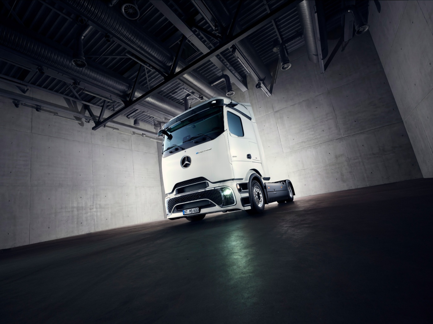 Autonomous truck chassis in industrial hall under dim lighting.