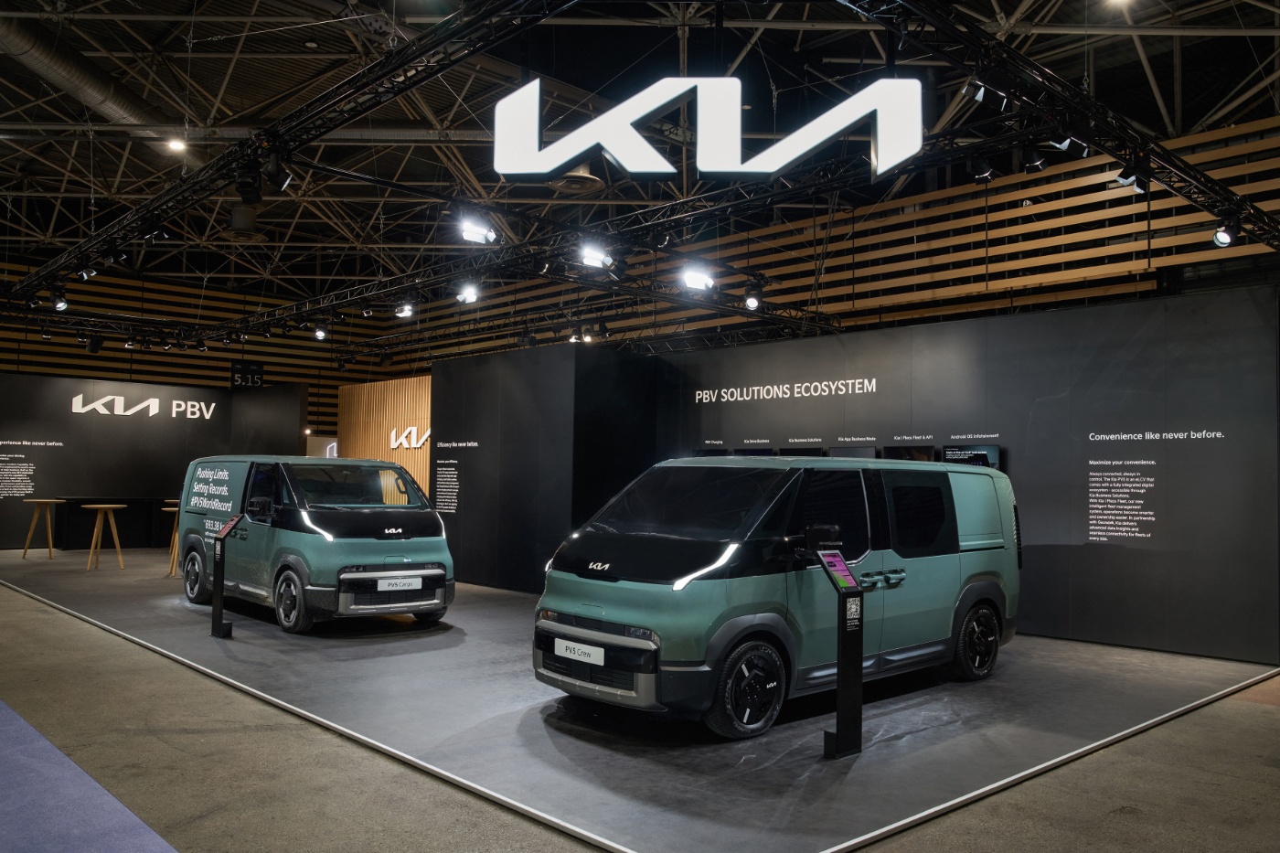 Two green Kia PBV vans displayed at an auto show booth with Kia logo above.
