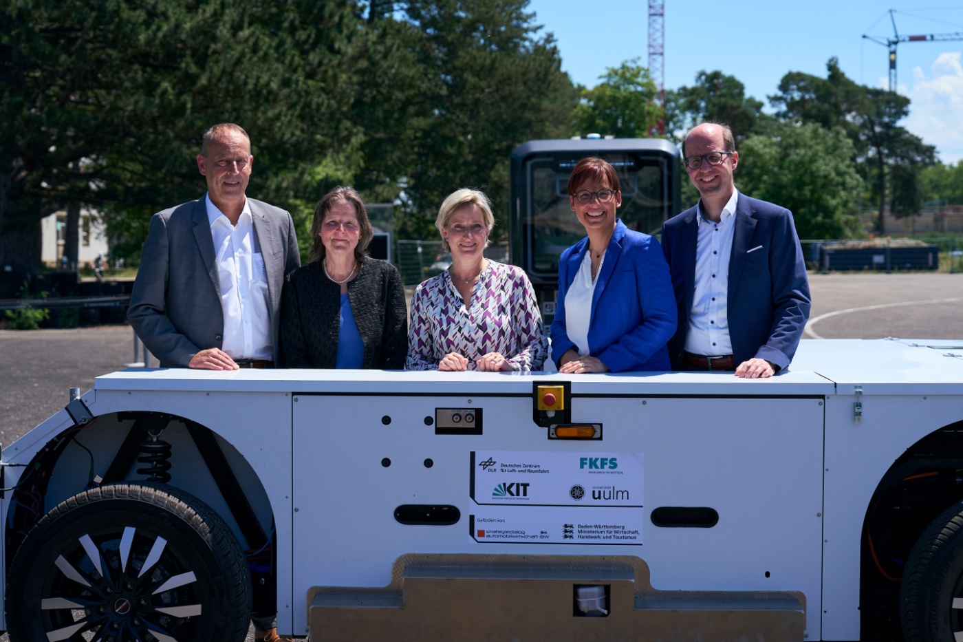 Five people standing behind the U-Shift autonomous transport platform outdoors.