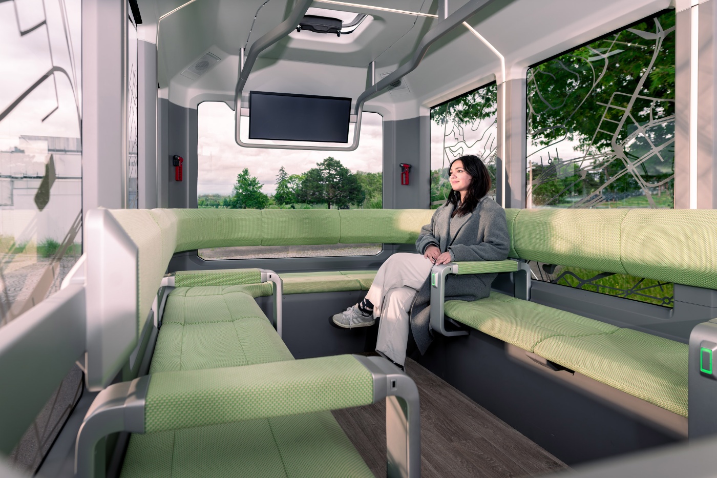 Passenger seated inside the U-Shift autonomous shuttle with bench seating.