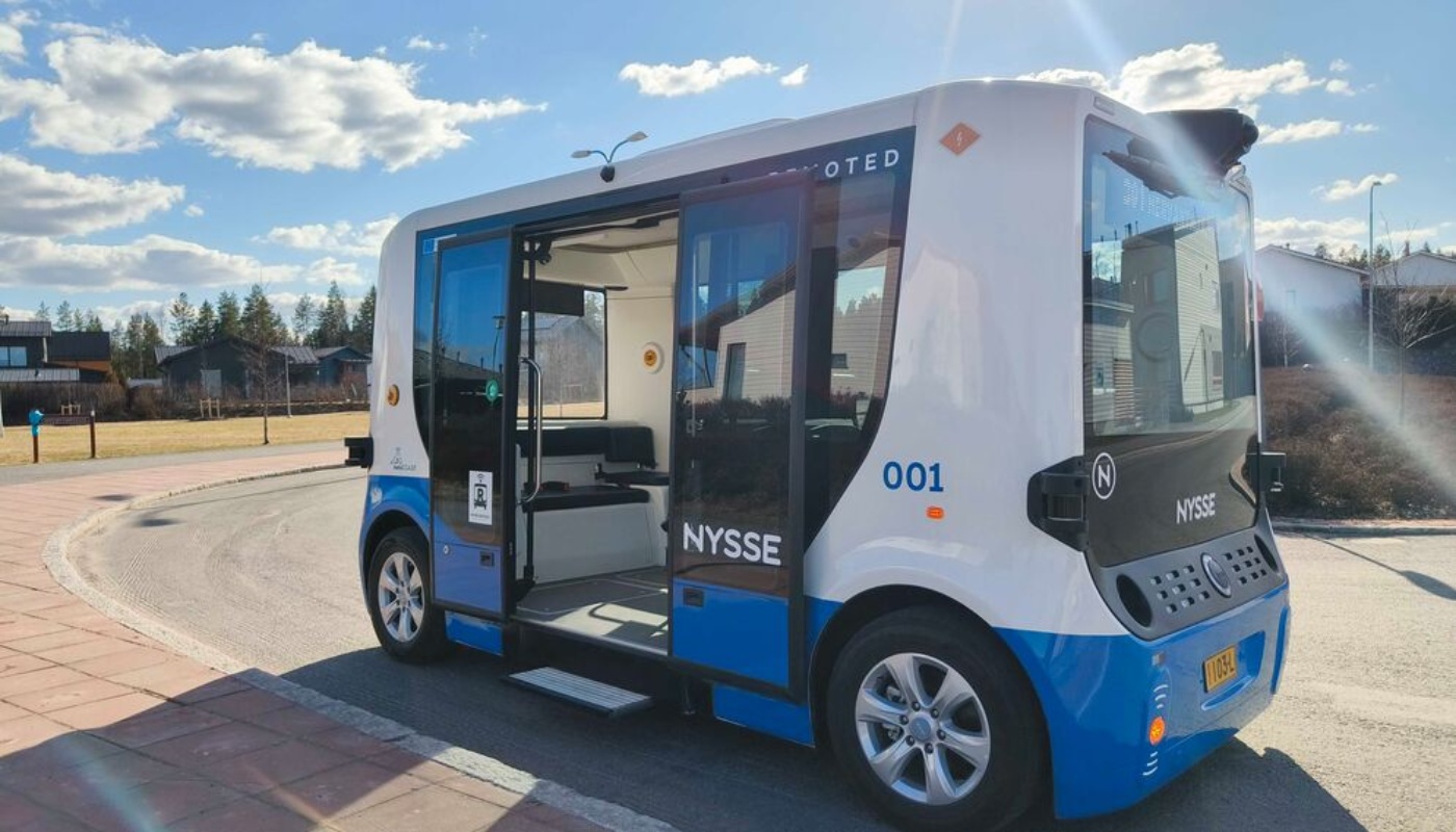 Autonomous electric shuttle bus with open doors at a stop.