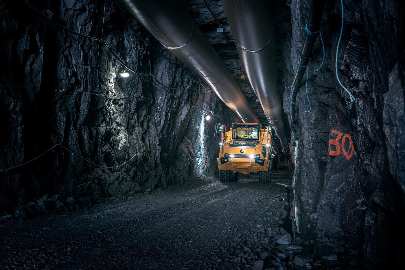 Orange Volvo truck driving through an underground mining tunnel.