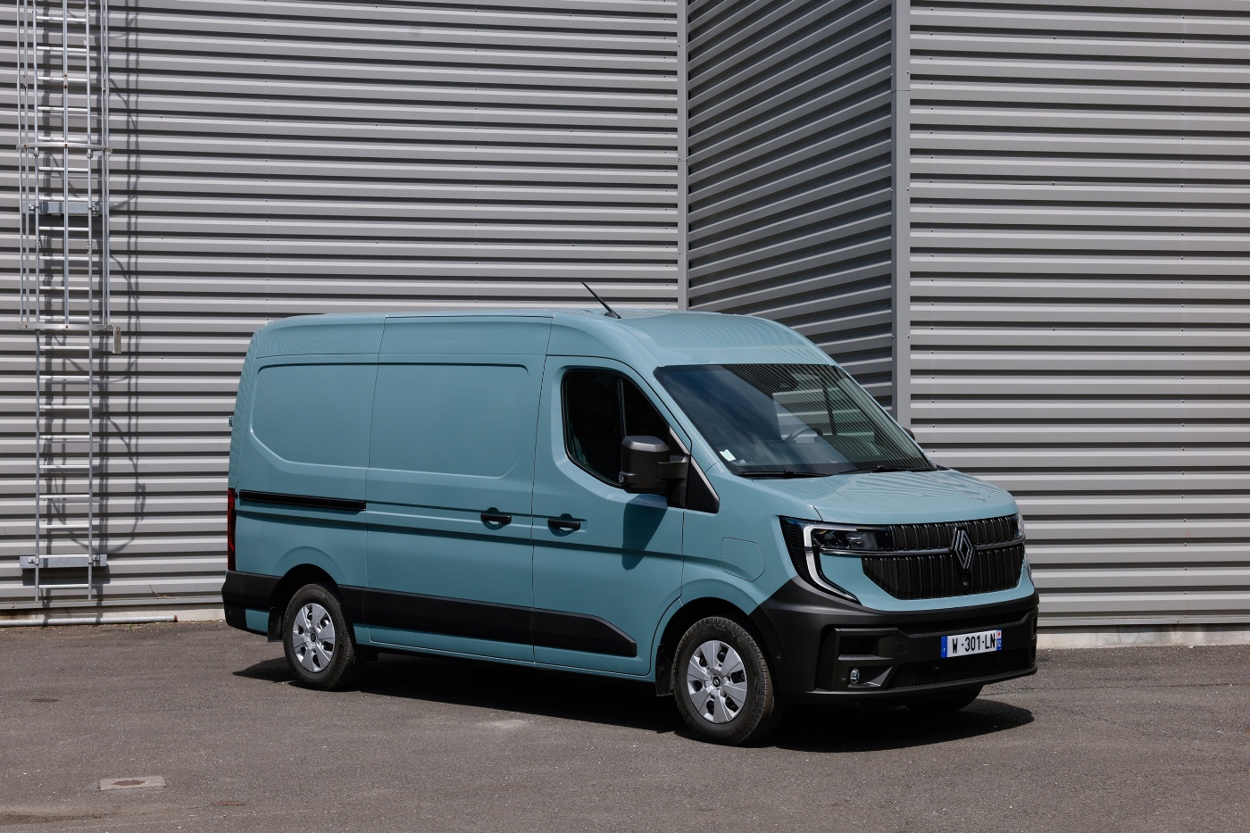 Light blue Renault panel van parked in front of an industrial building.