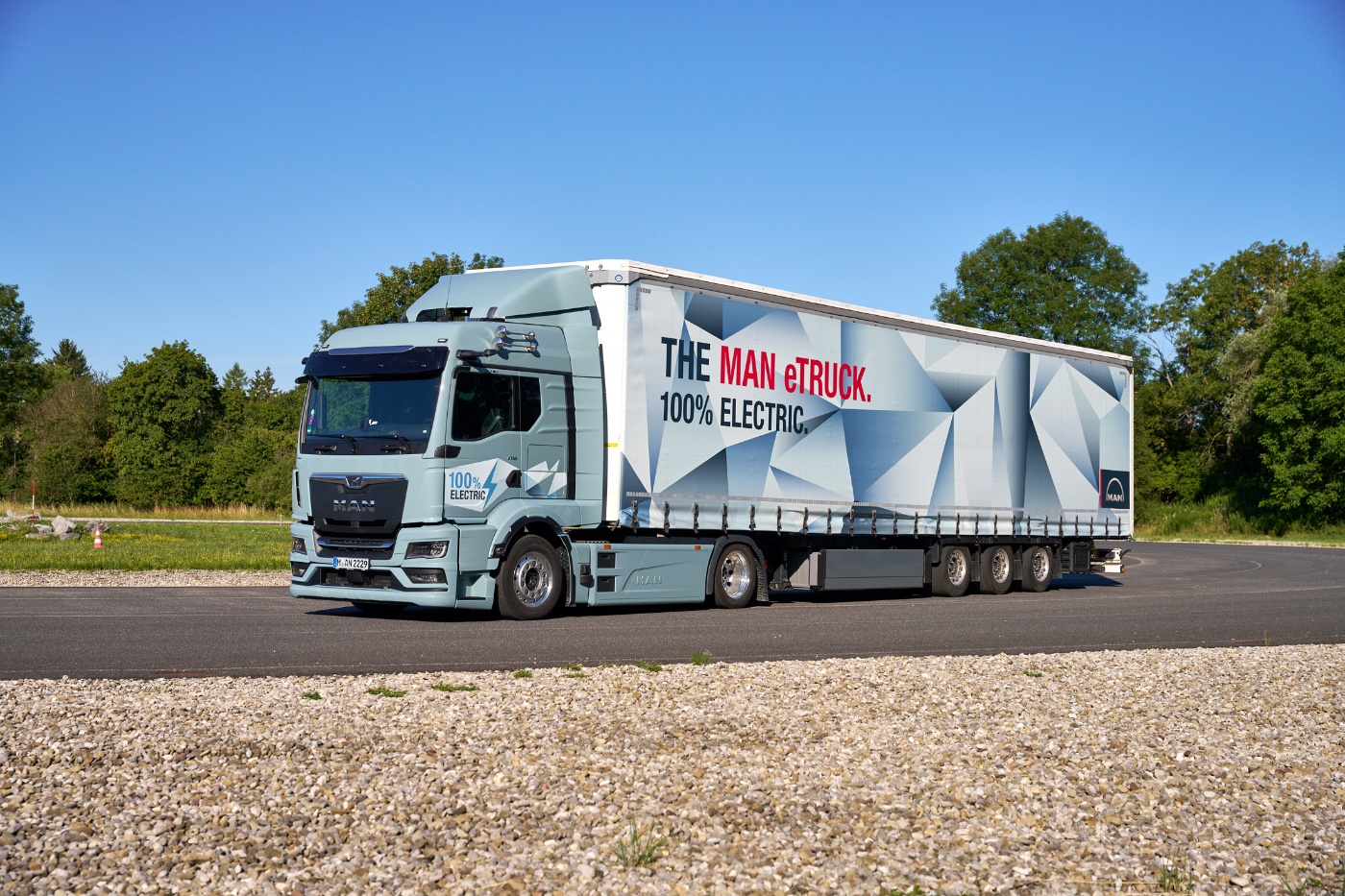 MAN truck with a trailer featuring a large graphic parked on a paved area.