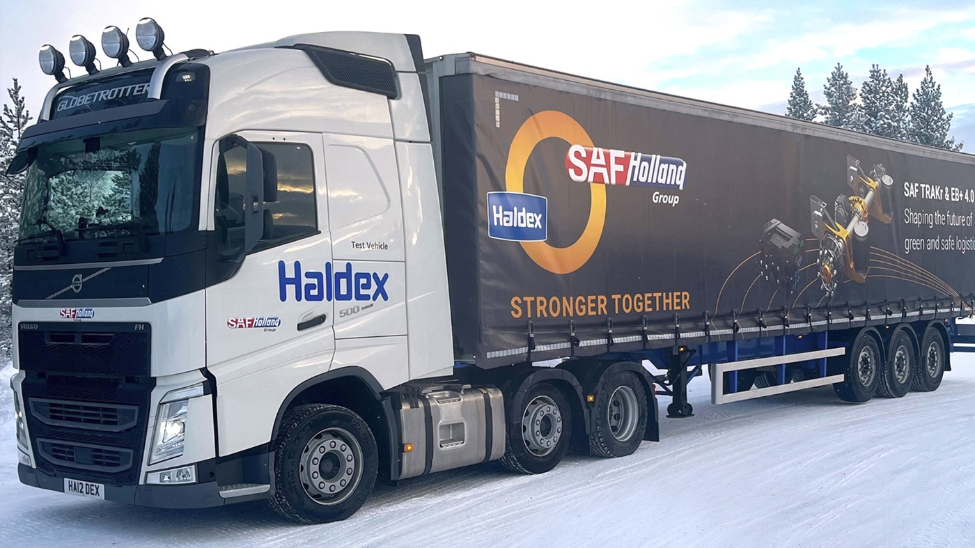 SAF-Holland truck with trailer driving on a snow-covered road.