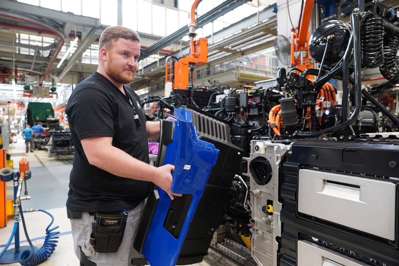 Mitarbeiter montiert ein MAN-Lkw-Bauteil an einer Produktionslinie.