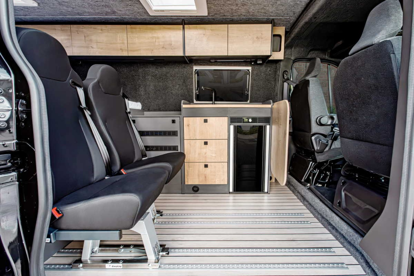 Innenraum eines Nissan-Campers mit Sitzen, Küchenzeile und Stauraum.