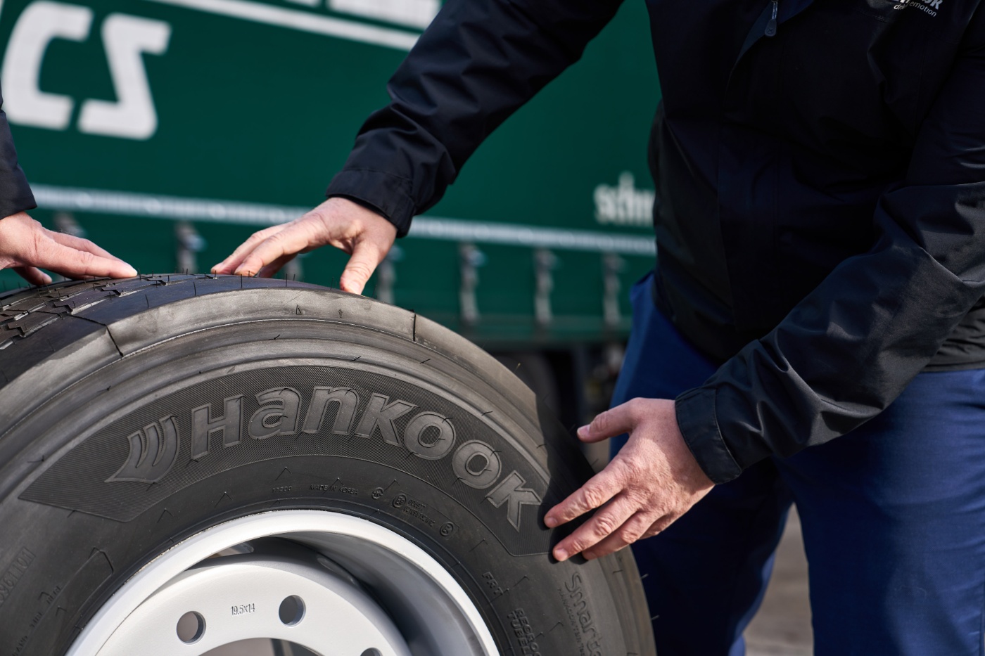 Hände prüfen einen Hankook-Lkw-Reifen auf einer Felge.