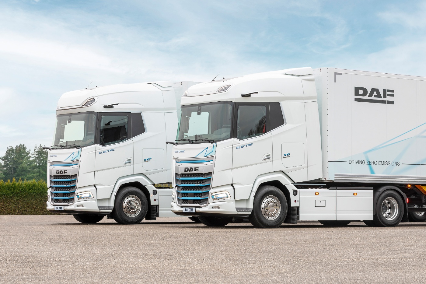 Two DAF electric trucks parked side by side outdoors.