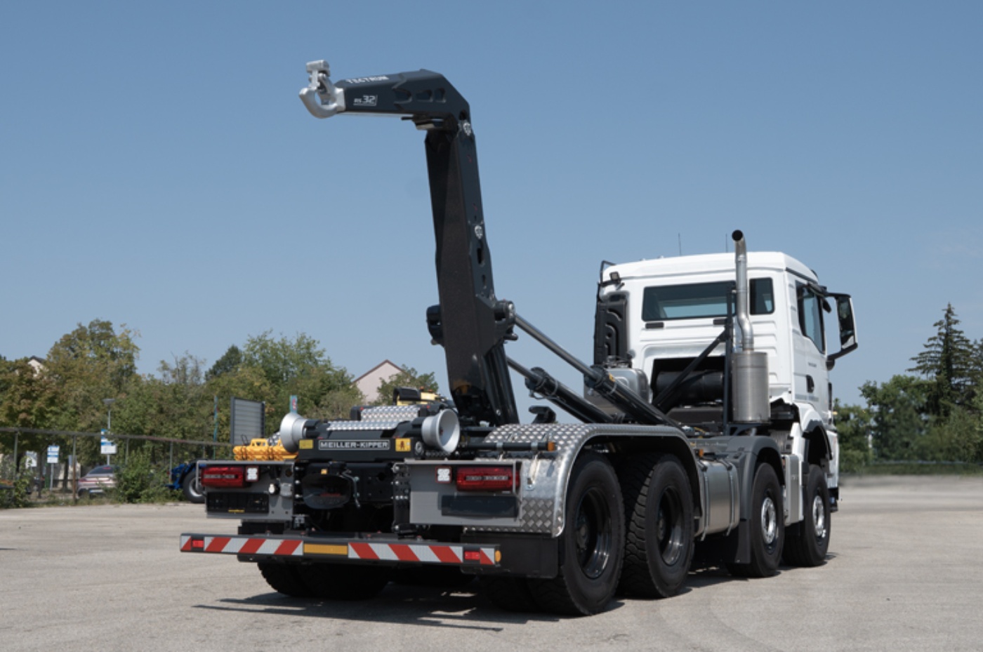 Meiller hooklift truck with a mounted lifting arm parked outdoors.