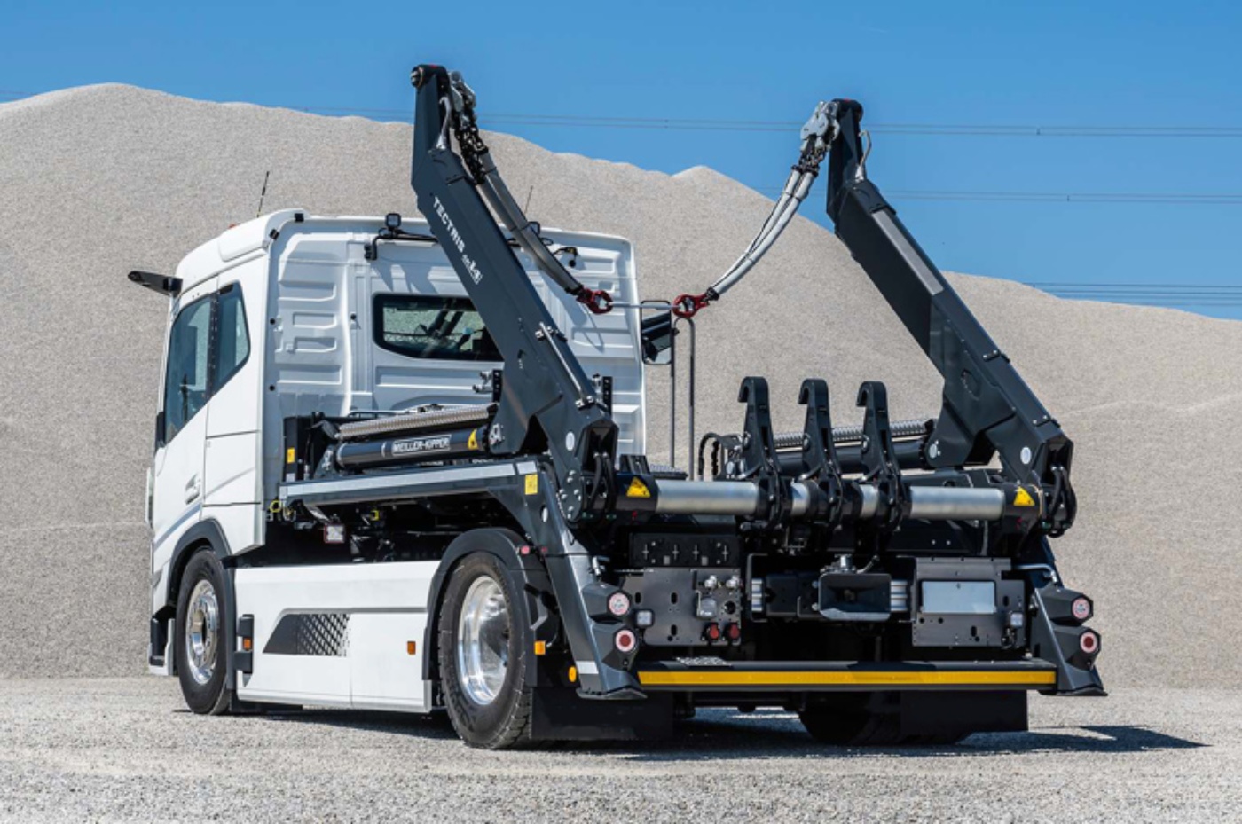 Meiller skip loader truck with dual lifting arms parked outdoors.