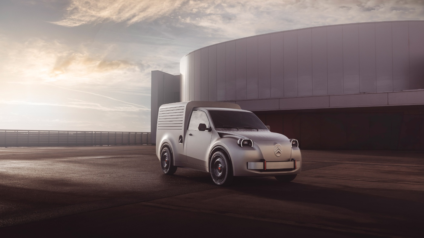 White Citroën delivery van parked in front of a large modern building at sunset.