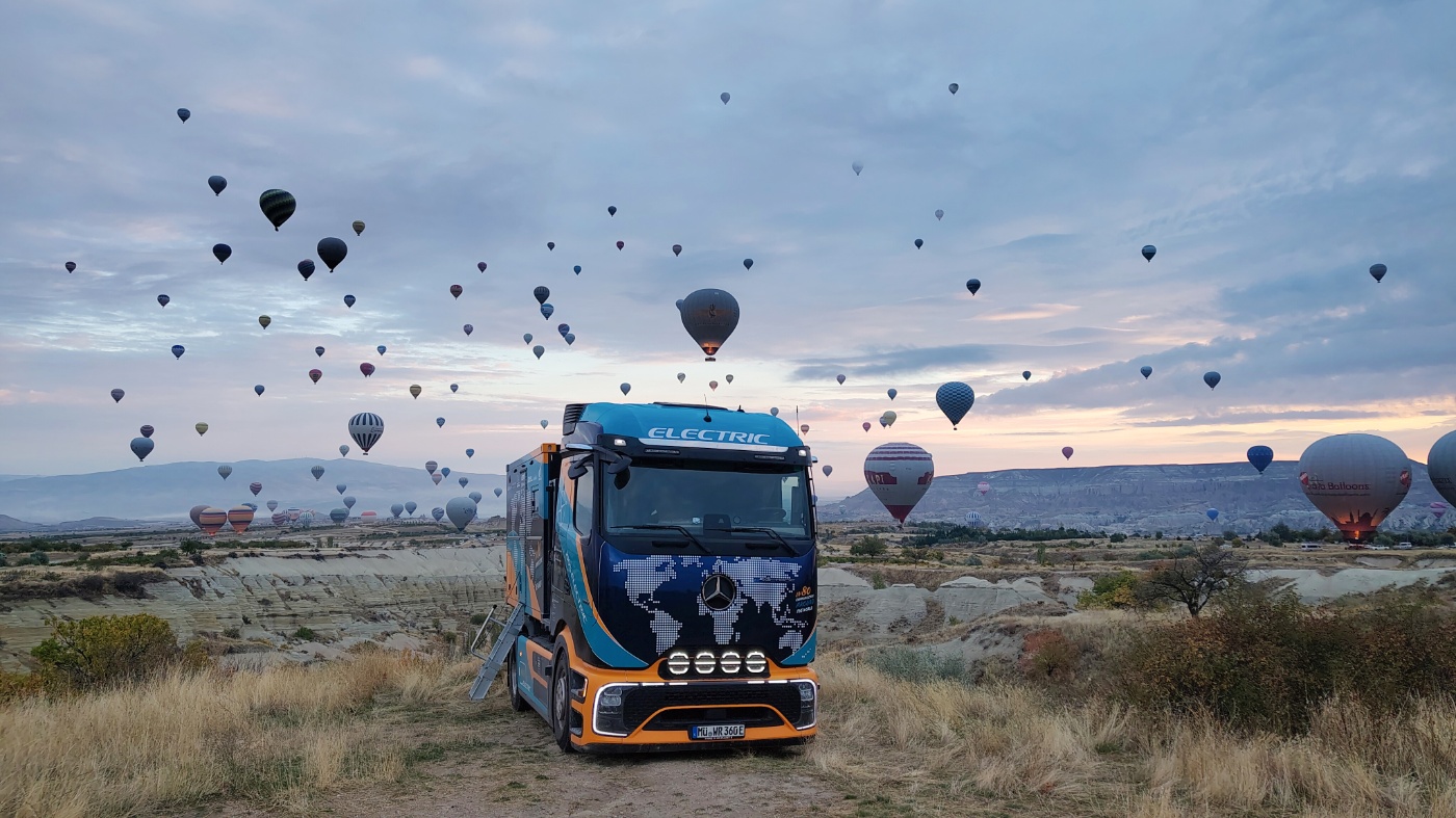 Elektrischer Mercedes-Benz-Lkw in einer Felslandschaft mit zahlreichen Heißluftballons am Himmel.